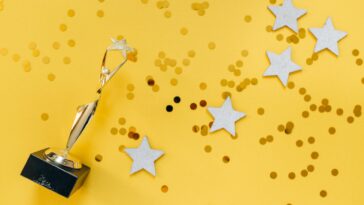 Shiny golden trophy and stars on a vibrant yellow background, symbolizing success and victory.