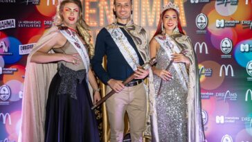 Three pageant winners pose in elegant attire with crowns and sashes at a vibrant event.