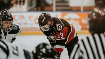Close-up action scene of ice hockey players in full gear competing on an indoor rink.