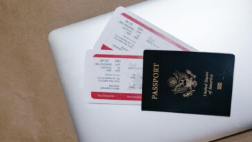 Close-up of a passport and boarding passes on a laptop, symbolizing travel preparation.