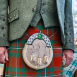 Close-up of a man wearing a traditional Scottish kilt with a sporran and jacket outdoors.