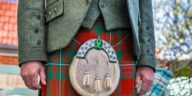 Close-up of a man wearing a traditional Scottish kilt with a sporran and jacket outdoors.