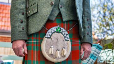 Close-up of a man wearing a traditional Scottish kilt with a sporran and jacket outdoors.