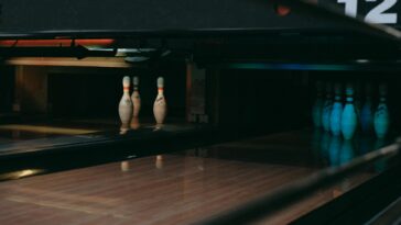 A dimly lit bowling alley showcasing lined-up pins ready for a strike.