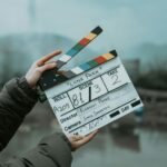Close-up of a film clapperboard on an outdoor set, signaling scene start.