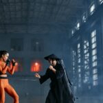 Two cosplayers in dynamic fighting pose inside industrial building.