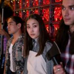 A group of diverse young adults on a film set, engaging in a creative production indoors.