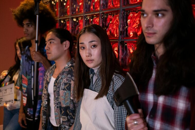 A group of diverse young adults on a film set, engaging in a creative production indoors.