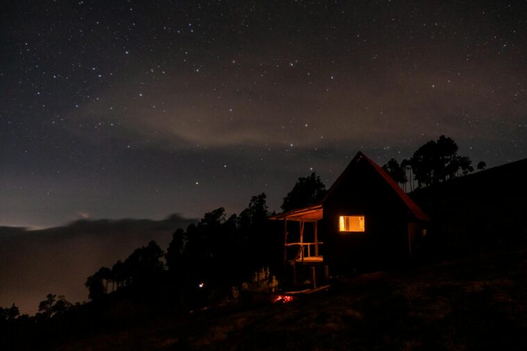 A beautiful silhouette of a cabin under a starry night sky, showcasing the peaceful outdoors.