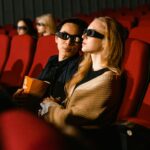 Young couple wearing 3D glasses enjoying a movie together in a cinema setting.