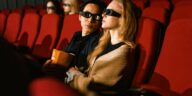 Young couple wearing 3D glasses enjoying a movie together in a cinema setting.