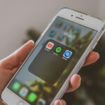 Hand holding a smartphone displaying popular music apps like Spotify and Shazam in a close-up shot.