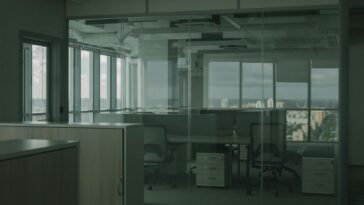 Spacious empty office with glass walls and city views, ideal for modern workspace settings.