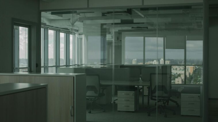 Spacious empty office with glass walls and city views, ideal for modern workspace settings.