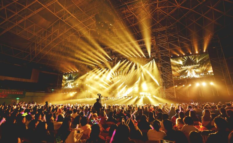 Dynamic concert scene with vibrant crowd and dazzling stage lights indoors.