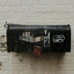 An old, weathered mailbox with peeling paint against a brick wall. Rustic and vintage charm.