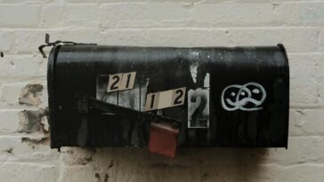 An old, weathered mailbox with peeling paint against a brick wall. Rustic and vintage charm.