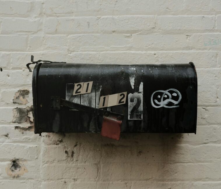 An old, weathered mailbox with peeling paint against a brick wall. Rustic and vintage charm.