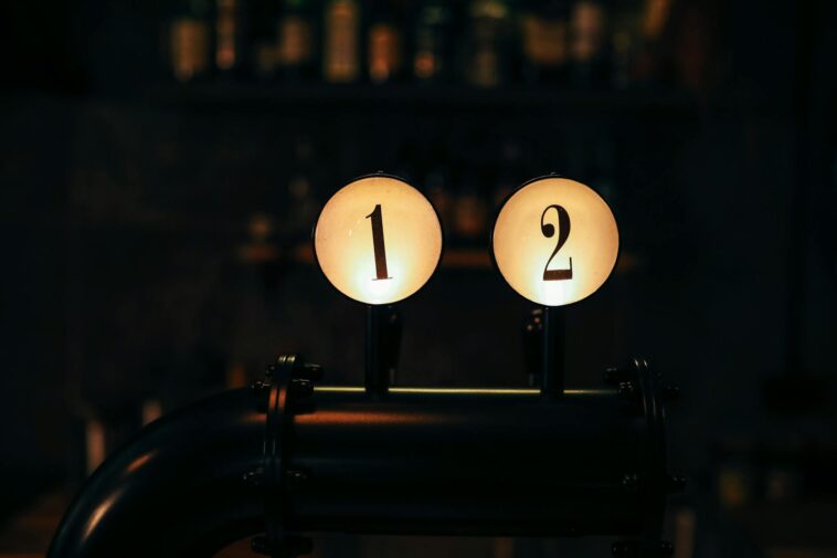 Close-up of numbered bar tap handles in a dimly lit vintage-style bar setting.