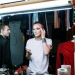 A drag queen applying makeup backstage, showcasing transformation and self-expression.