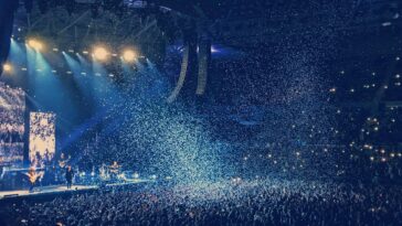 Energetic live concert with confetti and cheering crowd under bright stage lights.