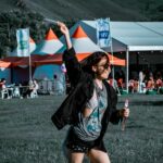 A woman joyfully plays with bubbles at an outdoor festival.