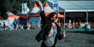 A woman joyfully plays with bubbles at an outdoor festival.