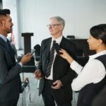 Journalists conduct an interview with a senior executive in a formal office setting.