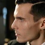 Close-up portrait of a man with a scar, exuding mystery and intrigue in a low-light setting.