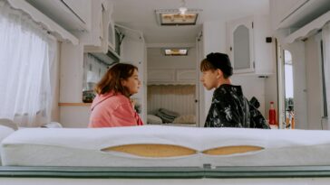 Two friends sit silently in a camper van, surrounded by a cozy interior.