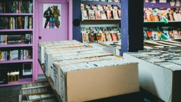 A colorful comic book store with organized shelves and boxes of comics for sale.