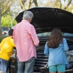 Grandfather and grandchildren inspecting car engine on a sunny day in Portugal.