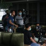 Film crew setting up camera equipment for indoor scene. Teamwork and filmmaking in action.