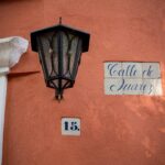 A street light casting shadows over a 'Calle de Juarez' sign and address number in Mexico City.
