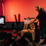 Film production team setting up a scene on an indoor set with dramatic lighting.