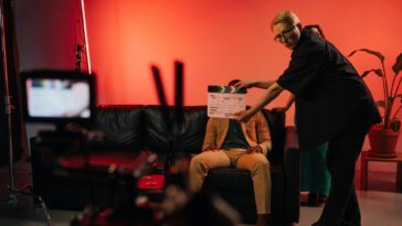 Film production team setting up a scene on an indoor set with dramatic lighting.