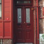 Cozy urban entrance featuring a red door and brick wall. Ideal for architecture themes.