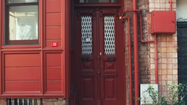 Cozy urban entrance featuring a red door and brick wall. Ideal for architecture themes.