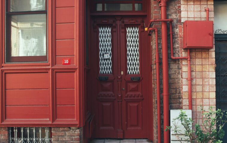 Cozy urban entrance featuring a red door and brick wall. Ideal for architecture themes.