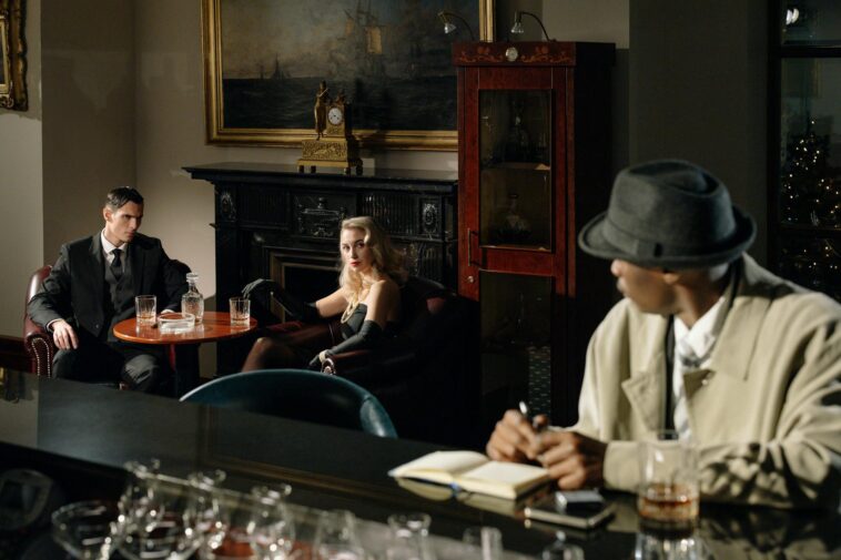 A detective watches a conversation unfold in a vintage lounge, capturing the essence of noir fiction.