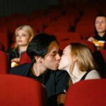 Romantic couple kissing in a cozy movie theater setting.
