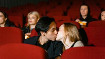 Romantic couple kissing in a cozy movie theater setting.