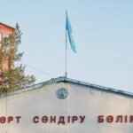 Fire station building in Konaev, Kazakhstan with the national flag on pole against a blue sky.