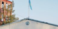 Fire station building in Konaev, Kazakhstan with the national flag on pole against a blue sky.