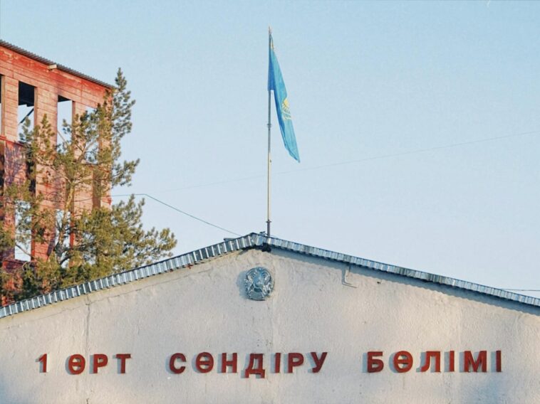 Fire station building in Konaev, Kazakhstan with the national flag on pole against a blue sky.