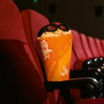 Cinema seat with popcorn and 3D glasses perfectly capturing the movie theater experience.