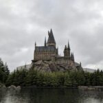 Majestic exterior view of Hogwarts Castle at Universal Studios Japan with a scenic water reflection.