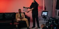 Professional film set with actor in suit, director using clapperboard.