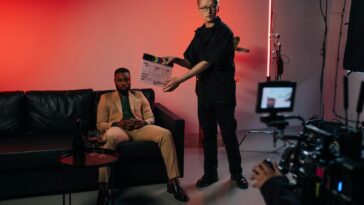 Professional film set with actor in suit, director using clapperboard.