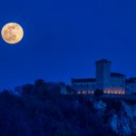 Majestic castle with a full moon at night, creating a dramatic and serene scene.